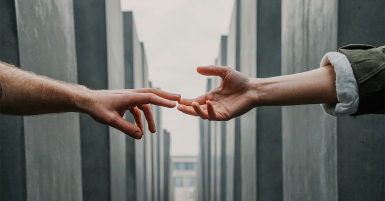 Two hands reach toward each other, meeting halfway across the image