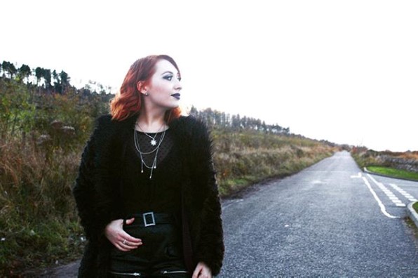 A Scottish fashion influencer poses on a rugged Scottish road