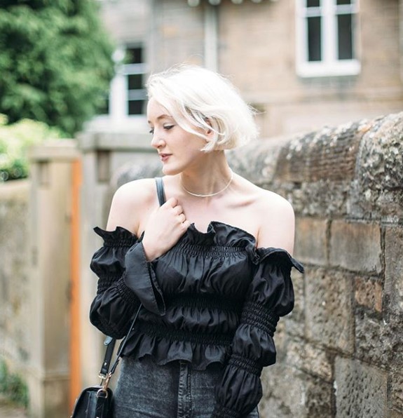 A Scottish fashion influencer posing on an old street