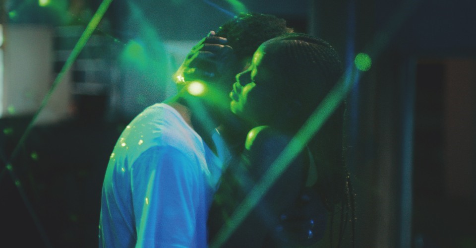 A still from film Atlantics (Mati Diop, 2019) showing a couple hugging under strong green lighting.