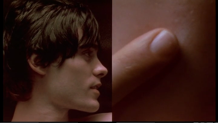 A screenshot from Darren Aronofsky’s Requiem for a Dream (2000) where a person puts a finger to skin.
