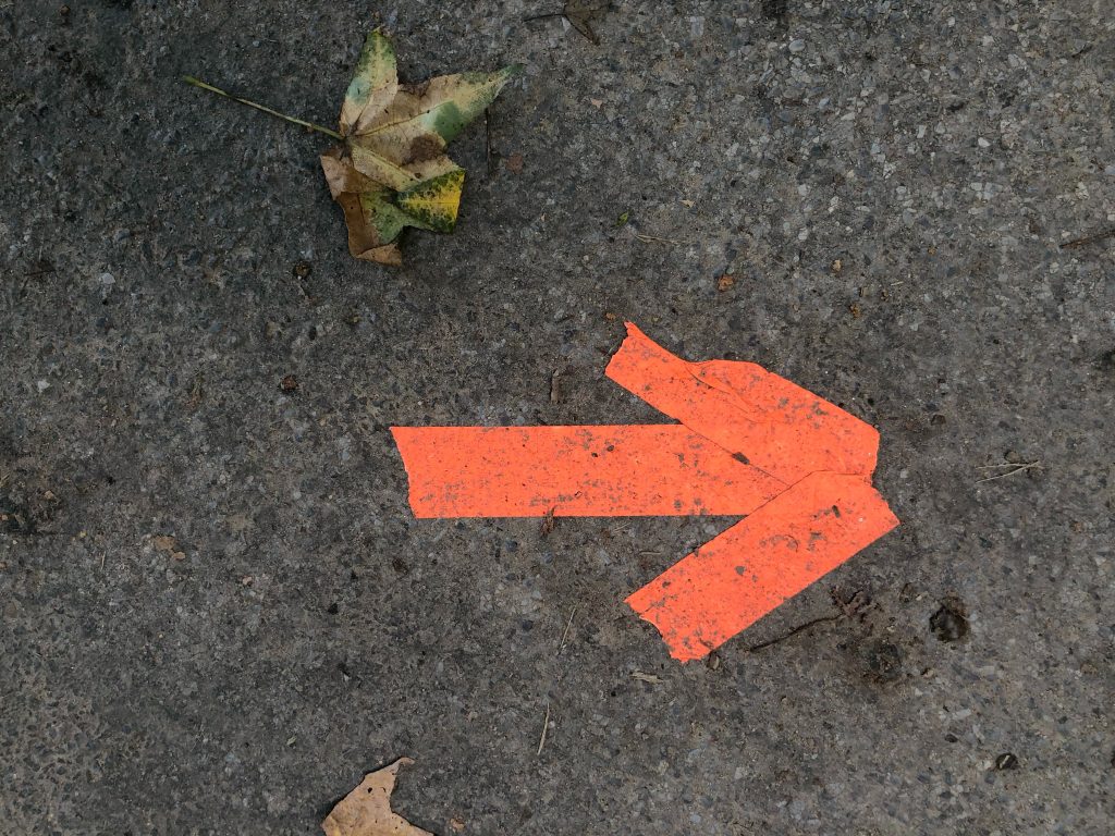 Three piece of red tape stuck to the ground formed into the shape of an arrow