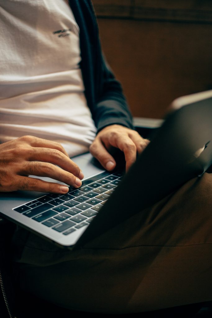 A pair of man's hands rest on a laptop