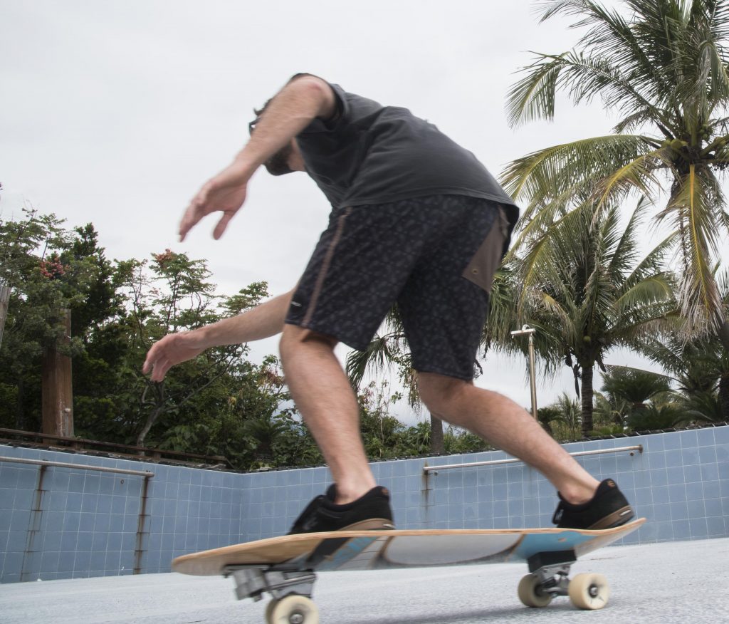 A man is on a skateboard, his back slightly bent as if preparing to do a trick