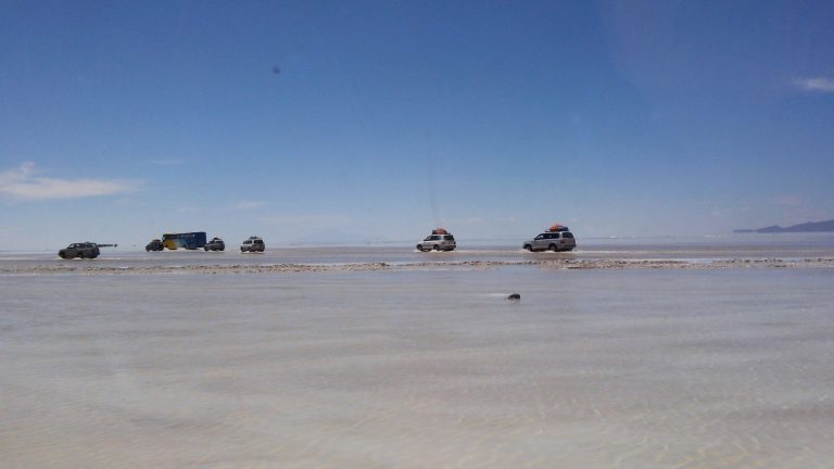 A photo of a beach with cars parked on the sand