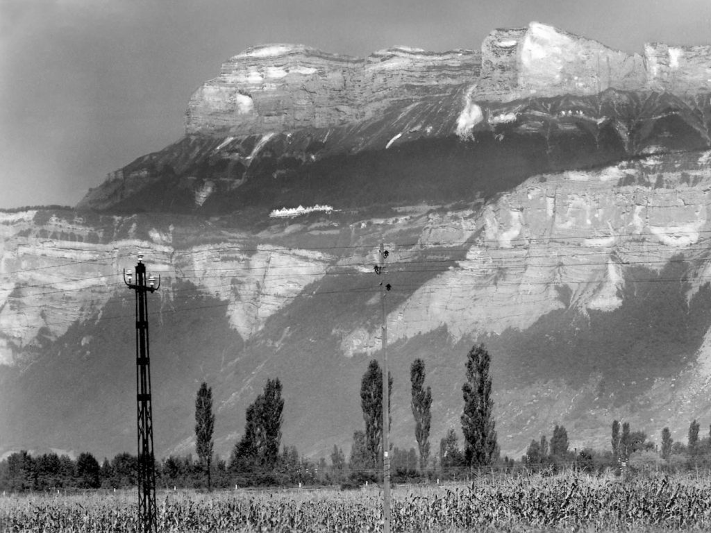 A black and white photo of a  field in front of a mountain