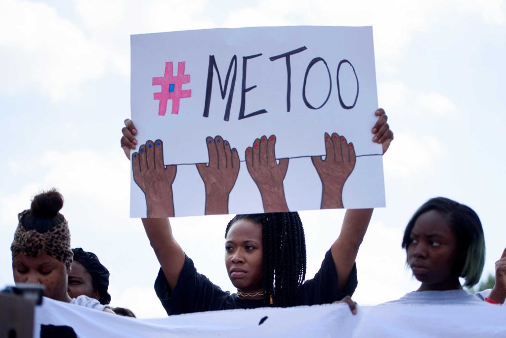  A woman holds up a sign that reads #MeToo