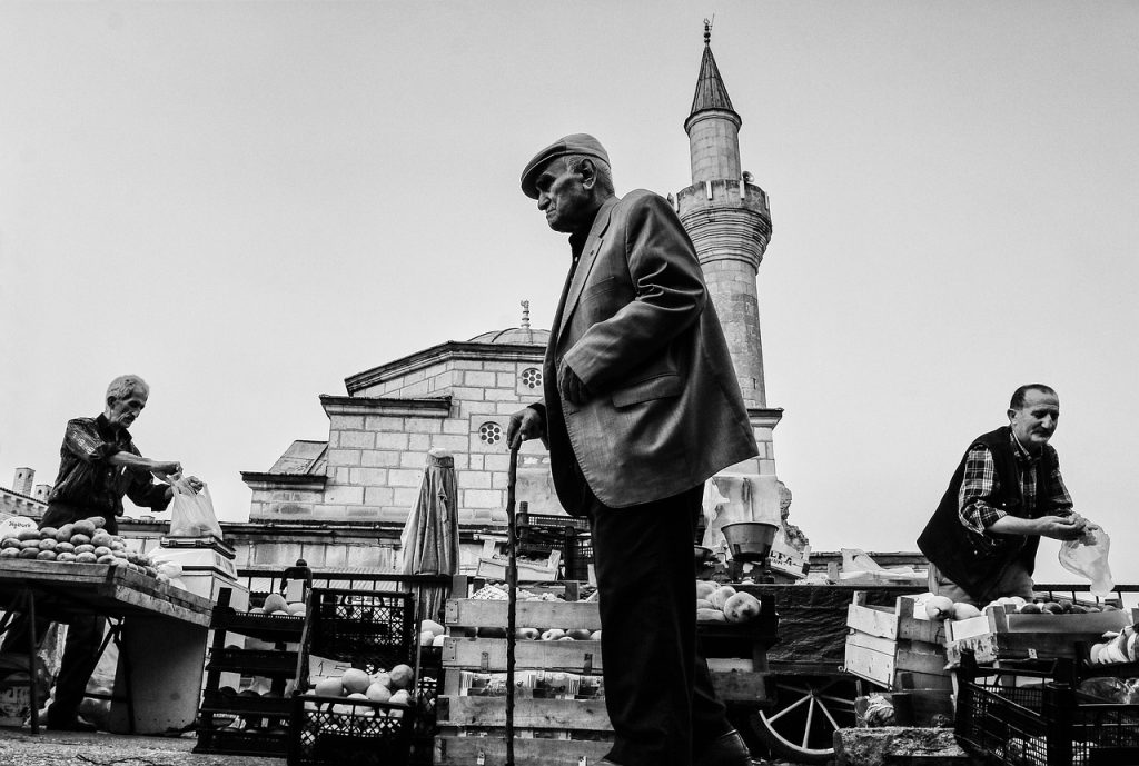 Preservation of a Nation: Friday preaching forms an important aspect of identity and nationalism in Turkey. Black and white photo of an old man in a market place in front of a Mosque.