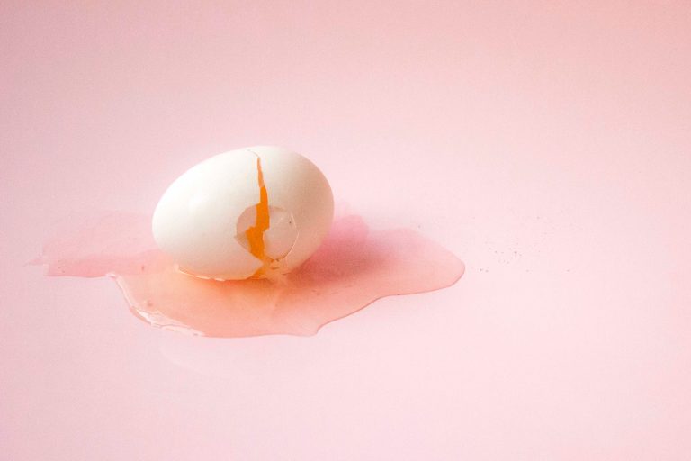 A cracked egg against a pink backdrop from Unsplash