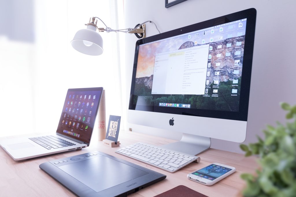 An Apple computer, laptop and smartphone on a desk