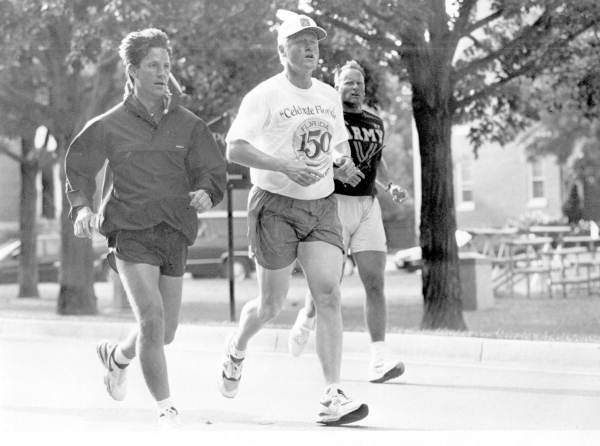 A black and white photo of former American President Bill Clinton running alongside two other men