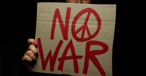 Woman holding "No War" placard with peace sign.