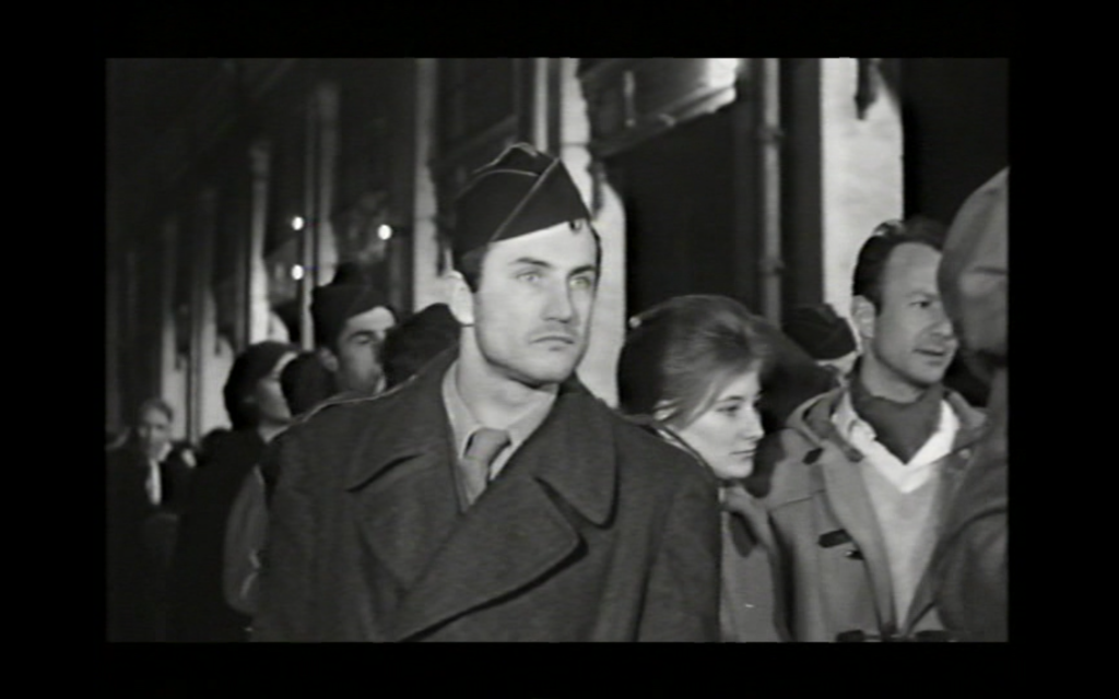 A man dressed in a veteran ensemble stares off into the distance in a crowd of people 