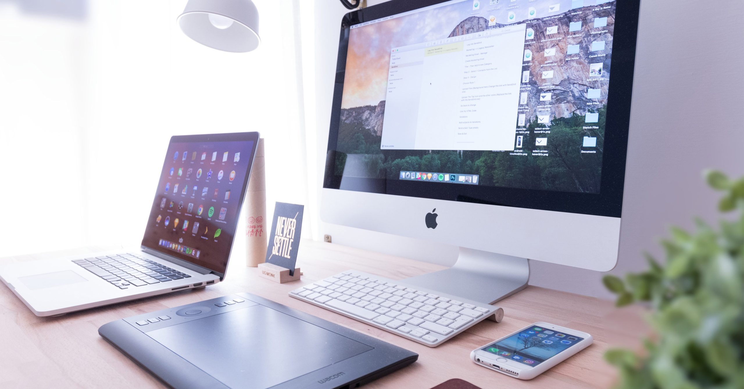 A collection of Apple devices, including a PC, laptop, iPad and iPhone on a desk