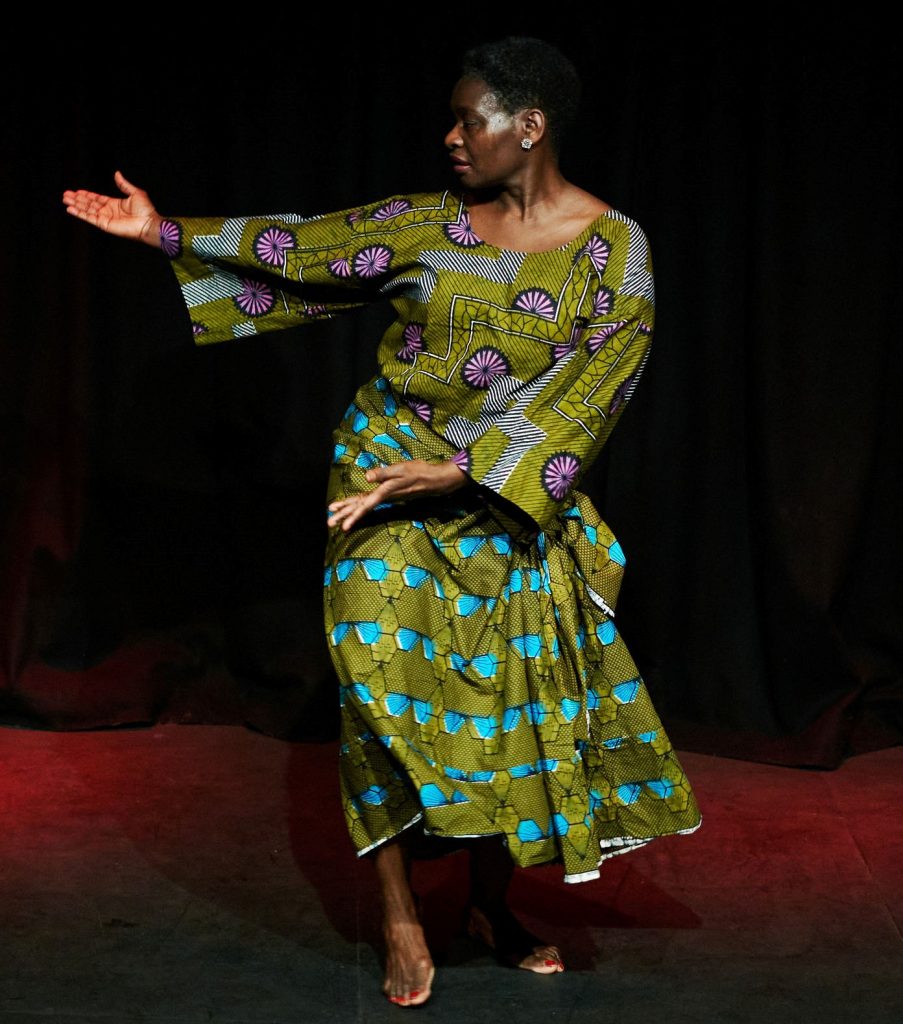 A woman in a green dress dances on a stage
