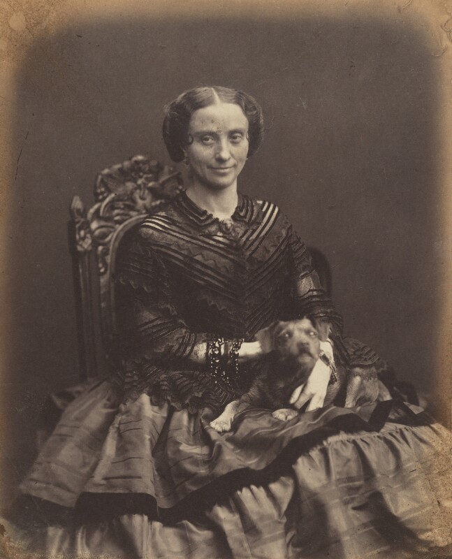 A black and white portrait of actress Madame Celeste sitting in a chair in a long dress posing for the camera