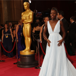 Lupita Nyong'o standing on the red carpet at the Oscars in a powder blue dress