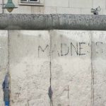 Photograph of the Berlin Wall, with the word 'madness' graffitied across it