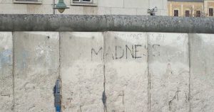 Photograph of the Berlin Wall, with the word 'madness' graffitied across it