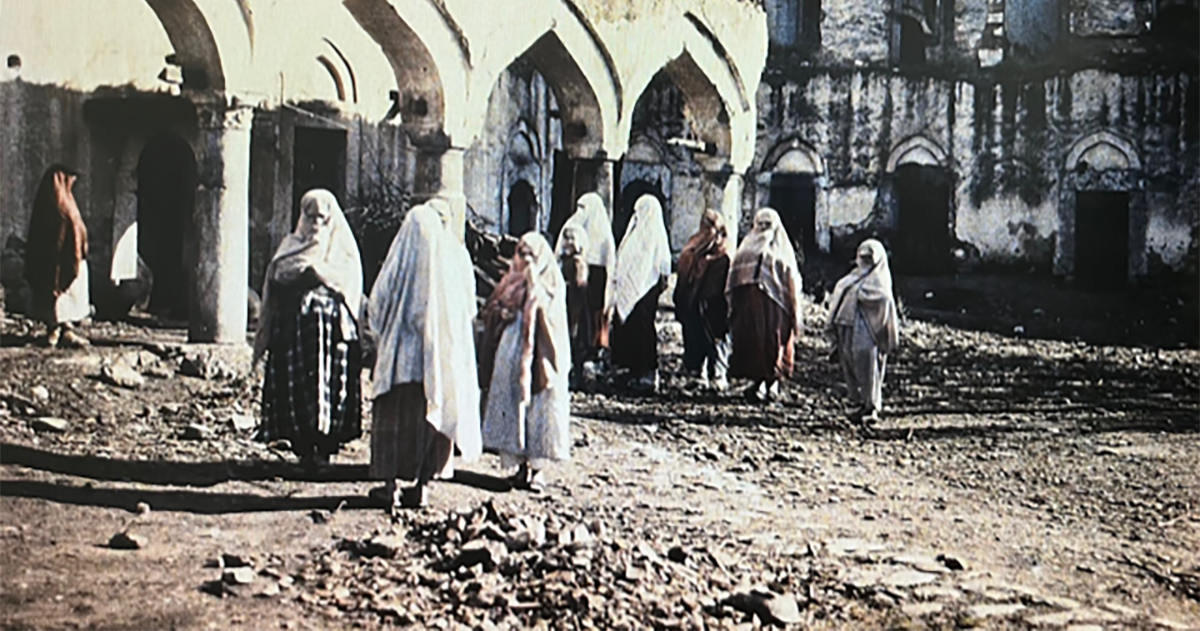 A group of Muslim women stand amongst the rubble of destroyed buildings