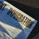 A page from a newspaper lying on the ground. The headline reads 'Immigration'.