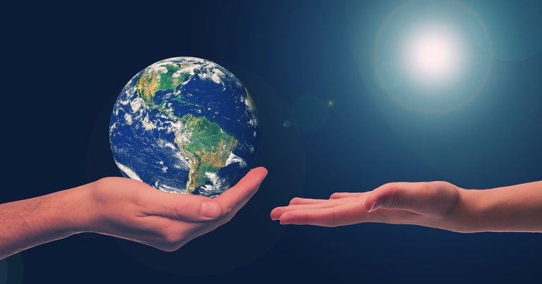 One hand holds the earth and passes it to another outstretched hand