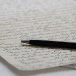 Photograph of a handwritten letter with a pen lying across it