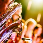 close-up photograph of a saxophonist playing with a band