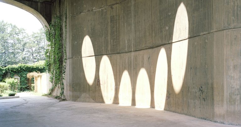Photograph of a concrete underpass with spots of sunlight shining on the walls