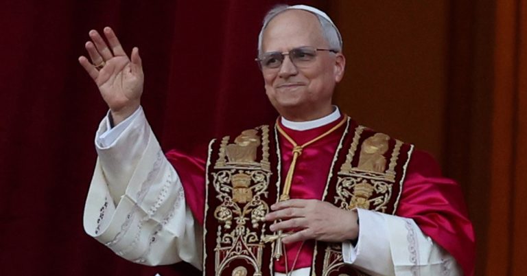 Pope Leo stands on a balcony waving