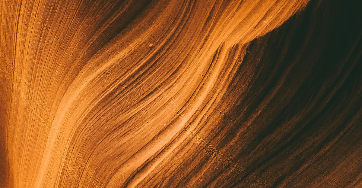 Layers of orange waves fade into a dark background