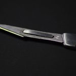 Photograph of a silver metal scalpel, taken from close-up, against a black background