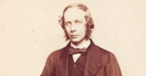 A black and white photo of a man dressed in a suit jacket and bowtie looking towards the camera