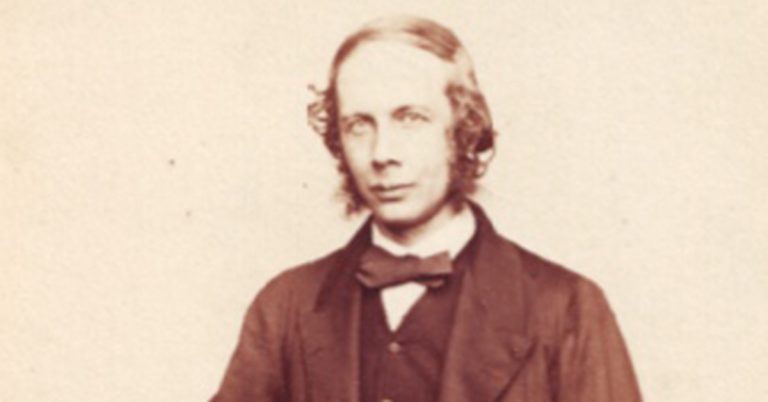 A black and white photo of a man dressed in a suit jacket and bowtie looking towards the camera