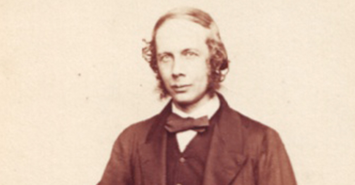 A black and white photo of a man dressed in a suit jacket and bowtie looking towards the camera