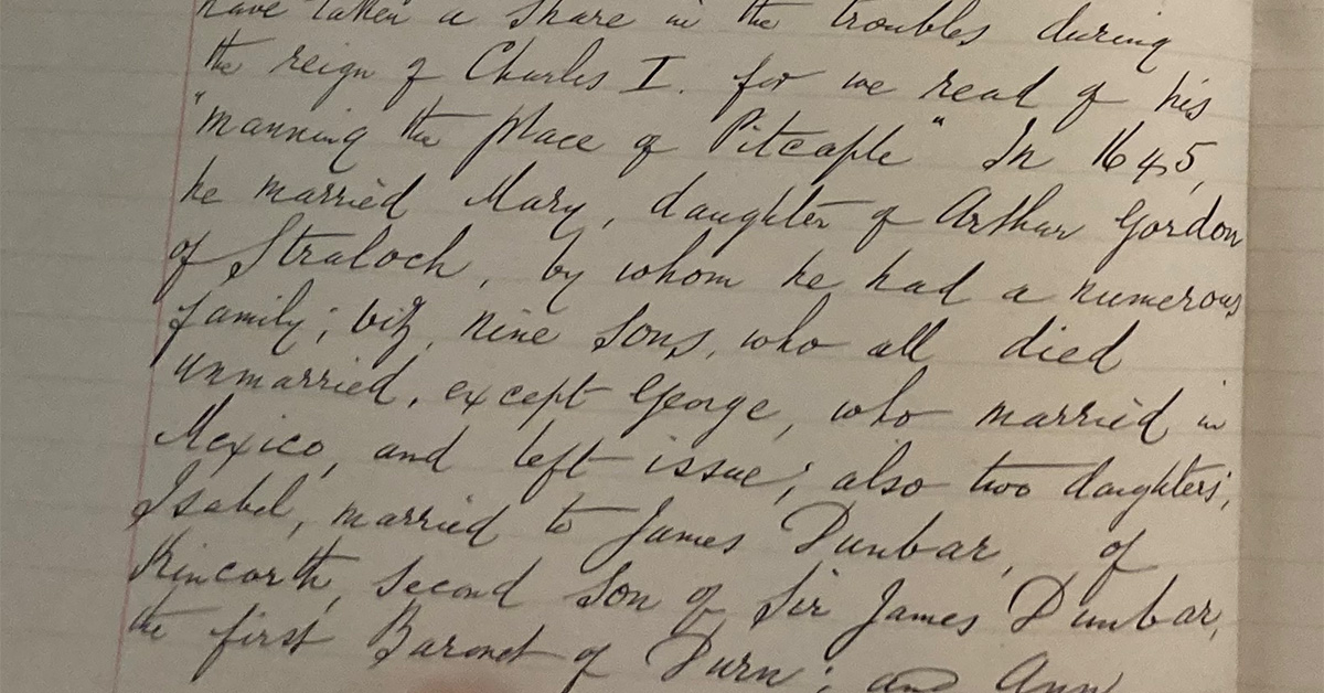 Close-up of a historical handwritten manuscript page in cursive ink, showing dense text on aged paper, held open by a person’s hand at the bottom edge.