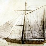 A sepia-toned historical drawing of a sailing ship with two masts. The vessel is shown in profile, featuring multiple rigging lines and sails—some raised and some partially furled. Small flags fly from the masts and stern. The style looks like an old technical or naval illustration, with fine line work detailing the ship’s structure and rigging.