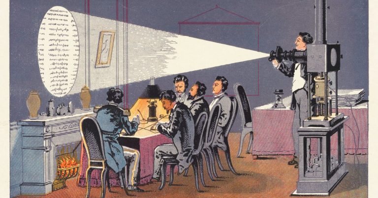 Five men in nineteenth-century tail coats are reading text projected onto a wall over a fireplace by a sixth man using a magic lantern.