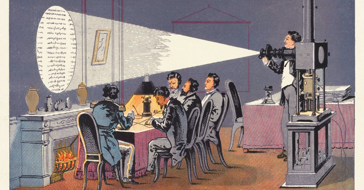 Five men in nineteenth-century tail coats are reading text projected onto a wall over a fireplace by a sixth man using a magic lantern.
