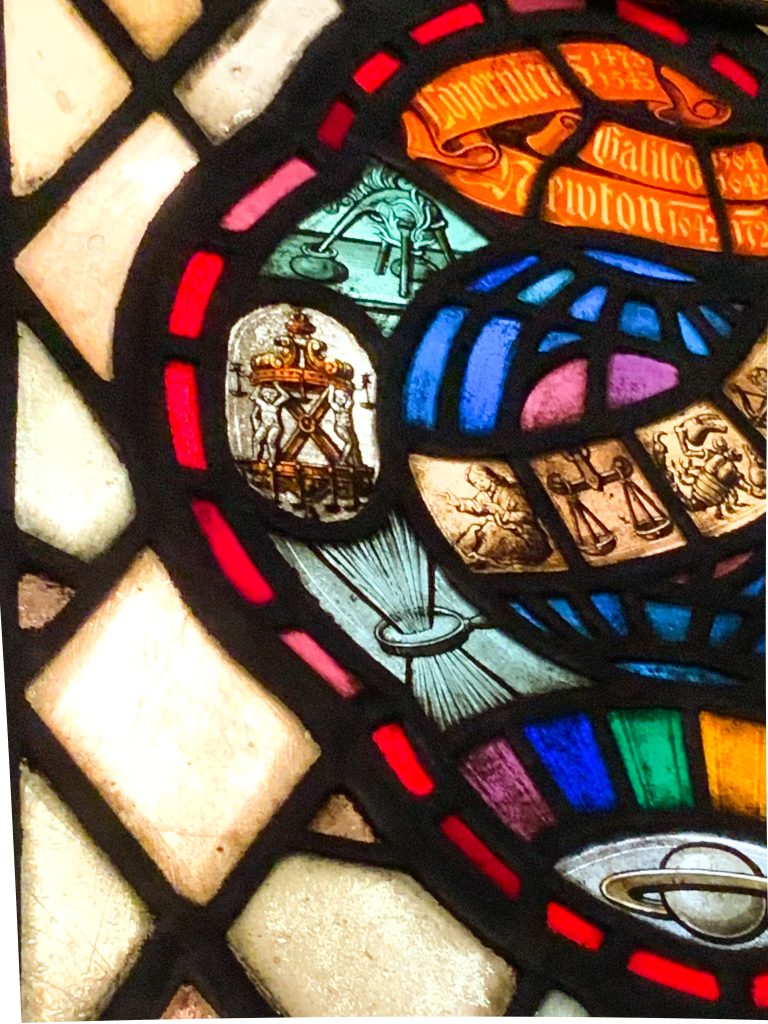 Multi-coloured stained glass featuring scientific iconography and the names of famous scientists, including Copernicus, Galileo, and Newton.